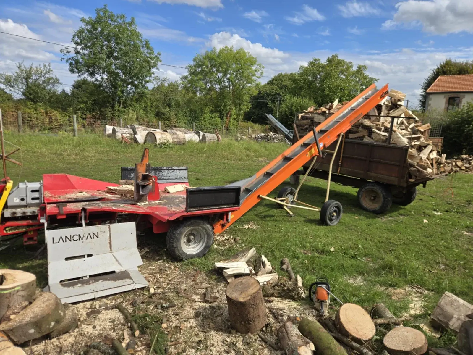 Fendeuse avec tapis convoyeur remplissant une remorque de bois de chauffage