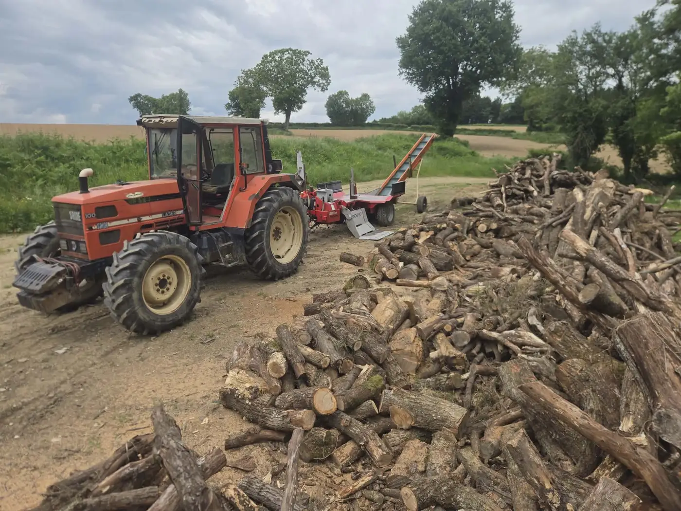 Tracteur, fendeuse et tas de bois de chauffage à fendre